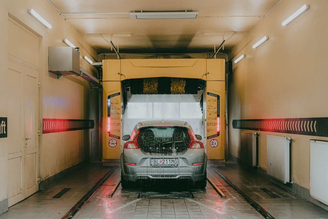A modern car undergoing an automated interior car wash with bright lights and soapy water.