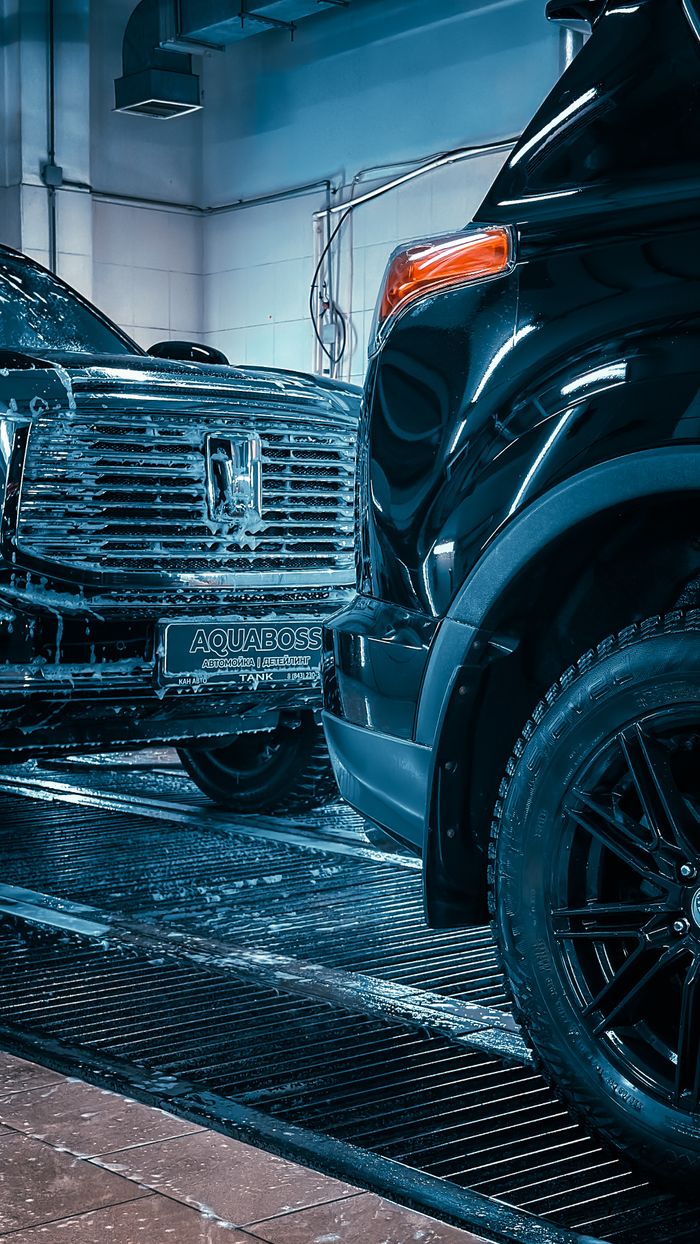 Close-up of luxury cars in a sleek, modern car wash, focusing on shiny surfaces and detailing.